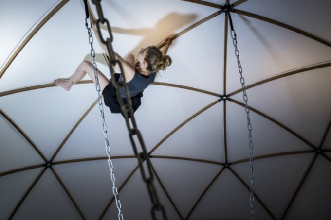 A photo of Agit Cirk's Jenni Lehtinen climbing across a tent at Brighton Fringe Festival's St Mark's Chapel spire in 2018