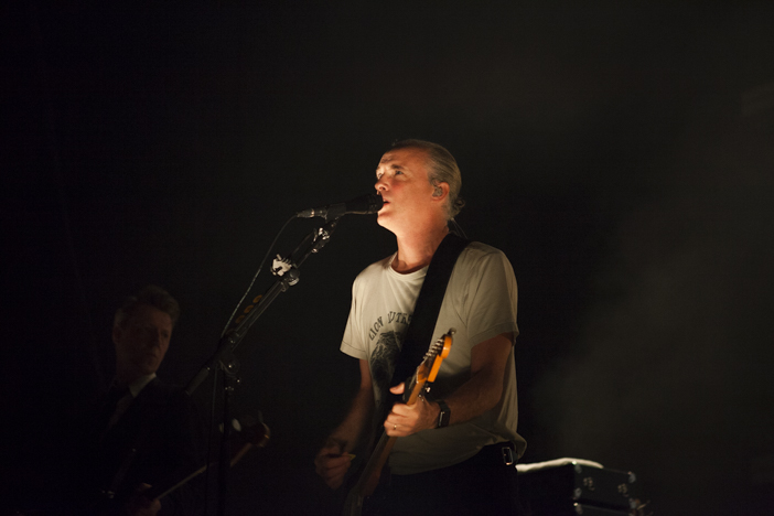 A photo of Fran Healy singing on stage while playing a guitar when as part of a Travis review at Brighton Dome