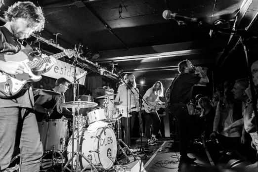 A photo of the band in a packed room in a photo by Sam Sesemann as part of an Idles review