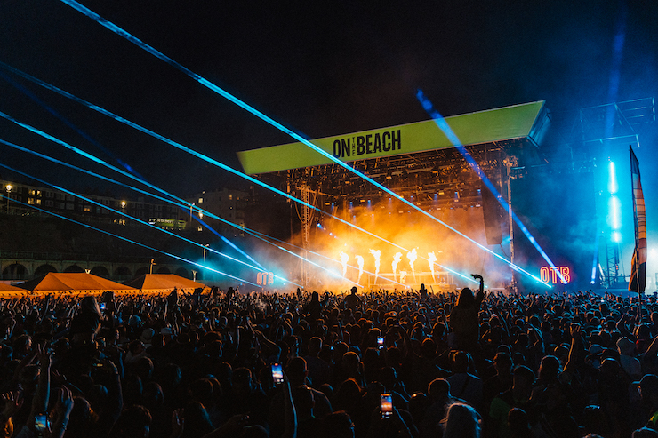 View of the crowd and stage at On The Beach Festival at night with strobe lighting