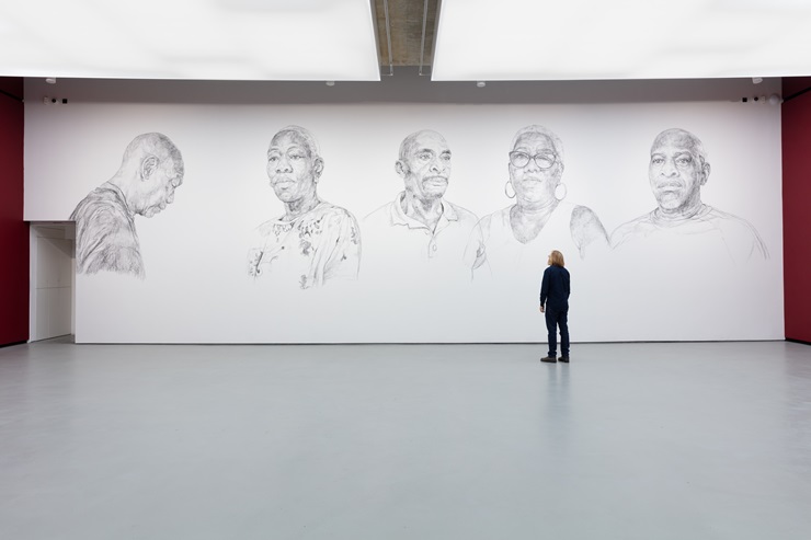 a person standing before charcoal mural of five portaits